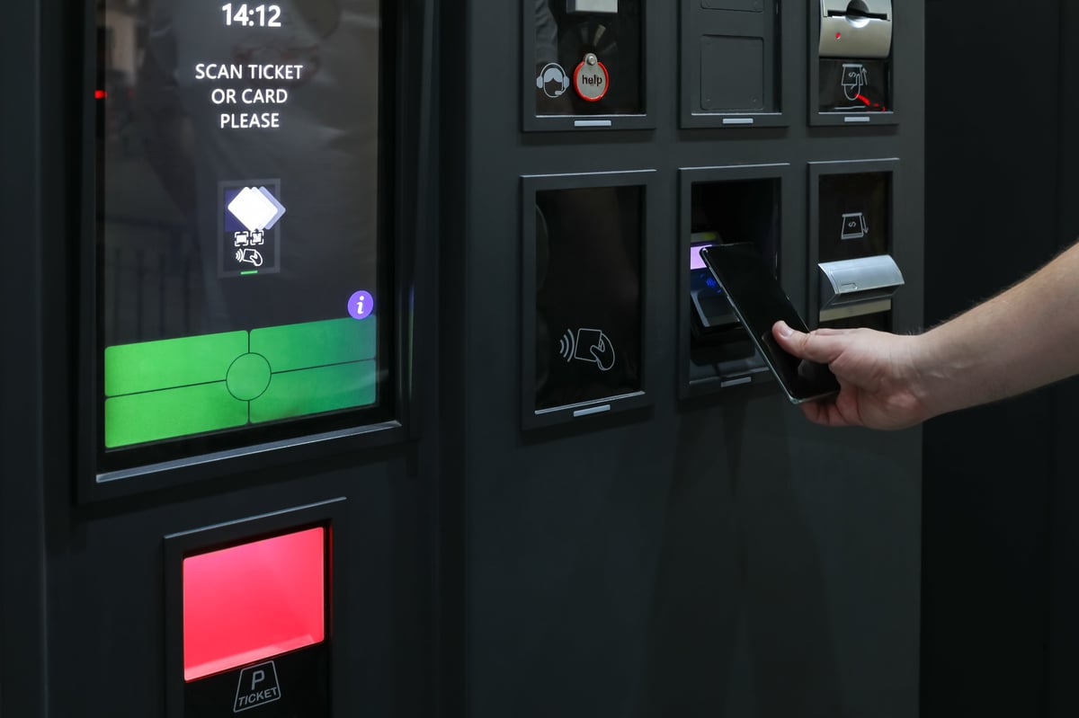 Contactless mobile parking payment at self-service machine, NFC smartphone scanning at automated parking terminal, digital cashless transaction, smart city transport technology concept.